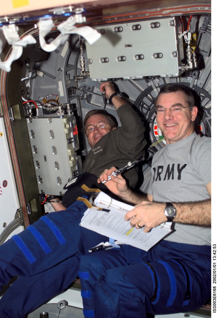 Astronauts Frank L. Culbertson, Jr., Expedition Three mission commander, and James S. Voss, Expedition Two flight engineer, perform routine tasks in the Unity node on the International Space Station (ISS). This image was taken with a digital still camera.