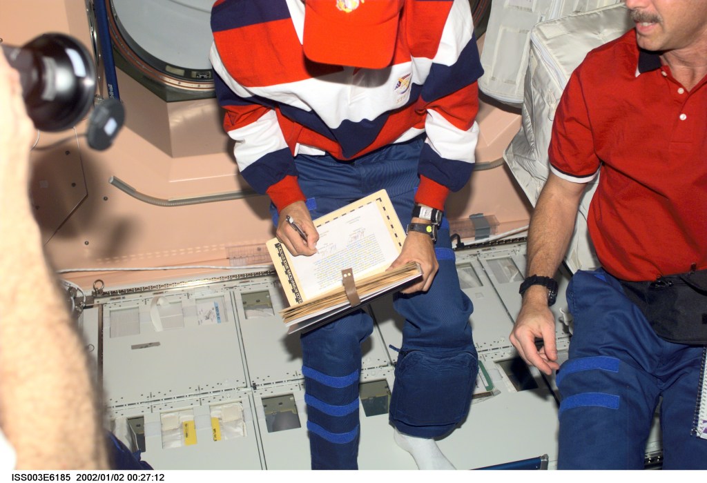 Astronauts Frederick W. (Rick) Sturckow (left), STS-105 pilot, and Scott J. Horowitz, mission commander, add their names to the ship’s log of visitors in the Unity node on the International Space Station (ISS). This image was taken with a digital still camera.