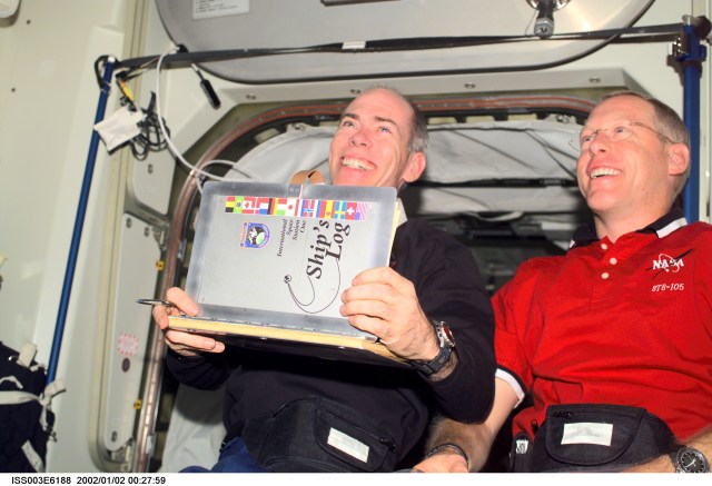 Astronauts Daniel T. Barry (left) and Patrick G. Forrester, both STS-105 mission specialists, add their names to the list of International Space Station (ISS) visitors in the ship’s log in the Unity node. This image was taken with a digital still camera.