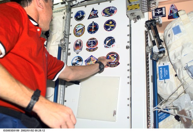Astronaut Scott J. Horowitz, STS-105 mission commander, adds the STS-105 crew patch to the growing collection of those representing Shuttle crews who have worked on the International Space Station (ISS). This image was taken with a digital still camera.