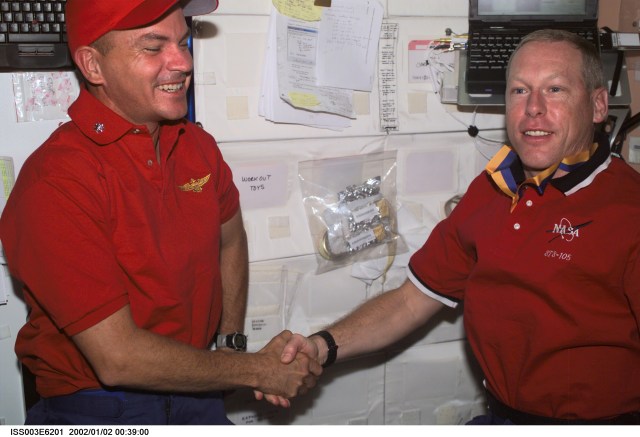 Astronauts Frederick W. (Rick) Sturckow (left), STS-105 pilot, and Patrick G. Forrester, mission specialist, exchange handshakes aboard the Unity node on the International Space Station (ISS). This image was taken with a digital still camera.