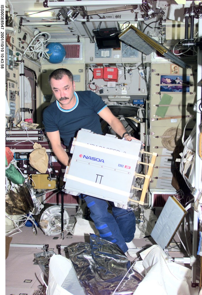 Cosmonaut Mikhail Tyurin, Expedition Three flight engineer representing Rosaviakosmos, works with Japan’s National Space Development Agency (NASDA) hardware for the Micro-Particles Capturer (MPAC) and Space Environment Exposure Device (SEED) experiment in the Zvezda Service Module on the International Space Station (ISS). This image was taken with a digital still camera.