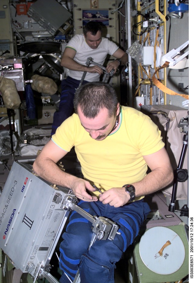 Cosmonauts Mikhail Tyurin (foreground) and Vladimir N. Dezhurov, both Expedition Three flight engineers, work with Japan’s National Space Development Agency (NASDA) hardware for the Micro-Particles Capturer (MPAC) and Space Environment Exposure Device (SEED) experiment in the Zvezda Service Module on the International Space Station (ISS). Tyurin and Dezhurov represent Rosaviakosmos. This image was taken with a digital still camera.