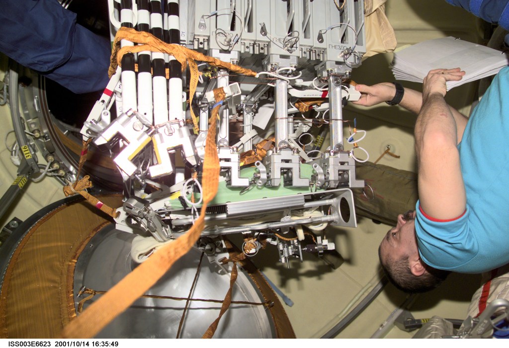 Cosmonaut Mikhail Tyurin, Expedition Three flight engineer representing Rosaviakosmos, works with hardware for the Micro-Particles Capturer (MPAC) and Space Environment Exposure Device (SEED) experiment and fixture mechanism in the Zvezda Service Module on the International Space Station (ISS). MPAC and SEED were developed by Japan’s National Space Development Agency (NASDA), and Russia developed the Fixture Mechanism. This image was taken with a digital still camera.