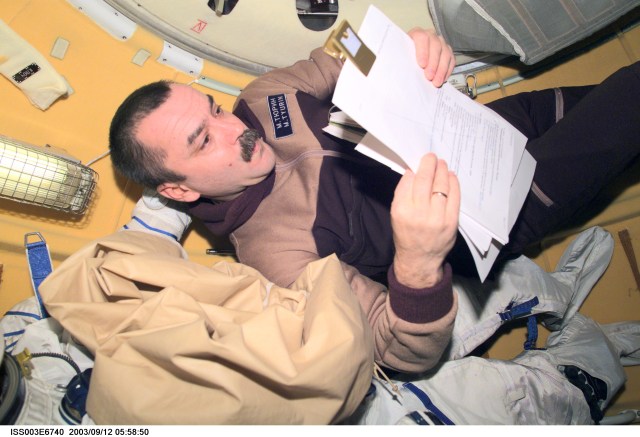 Cosmonaut Mikhail Tyurin, Expedition Three flight engineer representing Rosaviakosmos, reads a procedures check list in the Soyuz spacecraft which is docked to the International Space Station (ISS). This image was taken with a digital still camera.