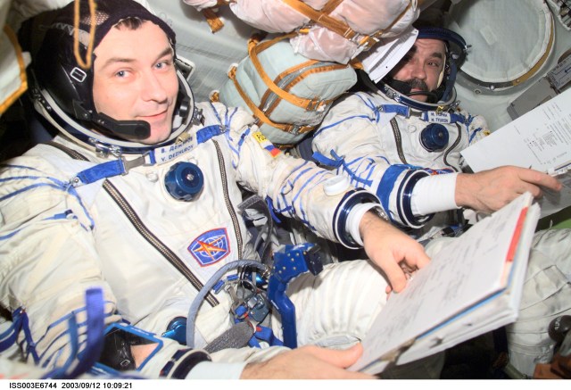 Cosmonauts Vladimir N. Dezhurov (left) and Mikhail Tyurin, both Expedition Three flight engineers, wearing Russian Sokol suits, are seated in the Soyuz spacecraft that is docked to the International Space Station (ISS). This Soyuz return vehicle will be moved from the Earth-facing port of the Zarya module for the linkup to the new Pirs Docking Compartment. The move of the Soyuz will mark the first time the new Pirs, which arrived at the station September 17, 2001, will serve as a docking port. The Soyuz will be shifted to prepare for the arrival of a new Soyuz return craft, to be launched October 21, 2001 from the Baikonur Cosmodrome in Kazakhstan. The Soyuz can serve as a crew return vehicle at the station for a maximum of about six months. Dezhurov and Tyurin represent Rosaviakosmos. This image was taken with a digital still camera.