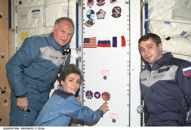 The Soyuz Taxi crewmembers, Commander Victor Afanasyev (left), French Flight Engineer Claudie Haignere and Flight Engineer Konstantin Kozeev, add their crew patch to the growing collection, in the Unity node, of insignias representing crews who have worked on the International Space Station (ISS). Afanasyev and Kozeev represent Rosaviakosmos, and Haignere represents ESA, carrying out a flight program for CNES, the French Space Agency, under a commercial contract with the Russian Aviation and Space Agency. This image was taken with a digital still camera.