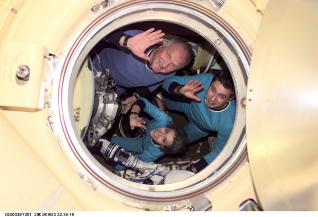 The Soyuz Taxi crewmembers wave from a Soyuz spacecraft docked to the International Space Station (ISS). Clockwise from the top are Commander Victor Afanasyev, Flight Engineer Konstantin Kozeev and French Flight Engineer Claudie Haignere. Afanasyev and Kozeev represent Rosaviakosmos, and Haignere represents ESA, carrying out a flight program for CNES, the French Space Agency, under a commercial contract with the Russian Aviation and Space Agency. This image was taken with a digital still camera by one of the Expedition Three crew from the nadir docking port on the station.