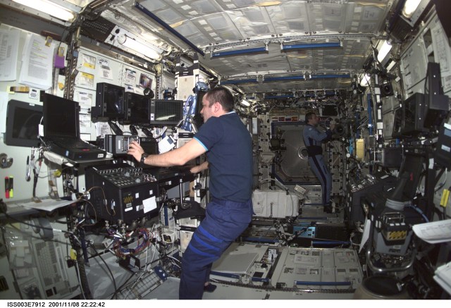 Cosmonaut Mikhail Tyurin (foreground), Expedition Three flight engineer, works the controls of the Canadarm2, or Space Station Remote Manipulator System (SSRMS) in the Destiny laboratory on the International Space Station (ISS). Cosmonaut Vladimir N. Dezhurov, flight engineer, is visible in the background. Tyurin and Dezhurov represent Rosaviakosmos. This image was taken with a digital still camera.
