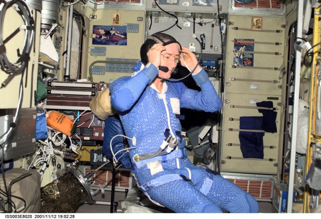 Astronaut Frank L. Culbertson, Jr., Expedition Three mission commander, wearing thermal undergarment, adjusts his communication headgear in the Zvezda Service Module on the International Space Station (ISS). This image was taken with a digital still camera.