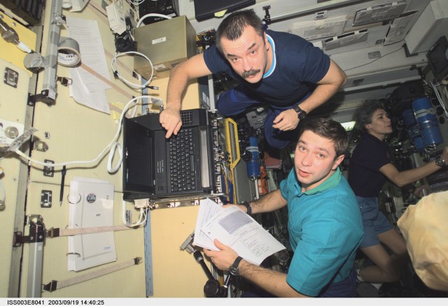 Cosmonaut Mikhail Tyurin (top), Expedition Three flight engineer, and Soyuz Taxi crewmembers, Flight Engineer Konstantin Kozeev and French Flight Engineer Claudie Haignere (background), work in the Zvezda Service Module on the International Space Station. Tyurin and Kozeev represent Rosaviakosmos, and Haignere represents ESA, carrying out a flight program for CNES, the French Space Agency, under a commercial contract with the Russian Aviation and Space Agency. This image was taken with a digital still camera.