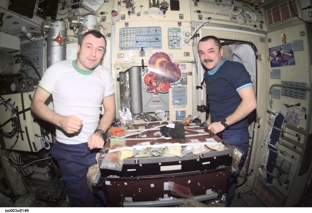 Cosmonauts Vladimir N. Dezhurov (left) and Mikhail Tyurin, both Expedition 3 flight engineers representing Rosaviakosmos, eat a Thanksgiving meal in the Zvezda Service Module on the International Space Station (ISS).