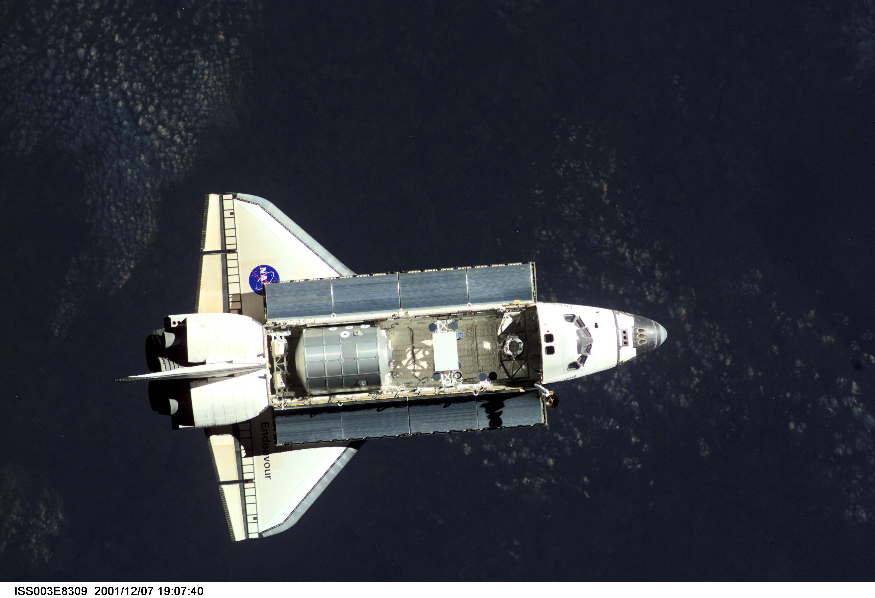 The Space Shuttle Endeavour, controlled by the flight crew of STS-108, is surrounded by darkness as it approaches the International Space Station (ISS). The Raffaello logistics module that is being brought up to the orbiting outpost is clearly visible in Endeavour's cargo bay. Among other activities the Endeavour's mission will include the change out of the station crews. The image was recorded with a digital still camera.