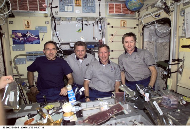 Astronaut Carl E. Walz (left), Expedition Four flight engineer; cosmonaut Yuri I. Onufrienko, Expedition Four mission commander; along with astronauts Dominic L. Gorie, STS-108 mission commander, and Frank L. Culbertson, Jr., Expedition Three mission commander, pose for a group photo in the Zvezda Service Module on the International Space Station (ISS). Various food items are visible in the foreground. The image was taken with a digital still camera.