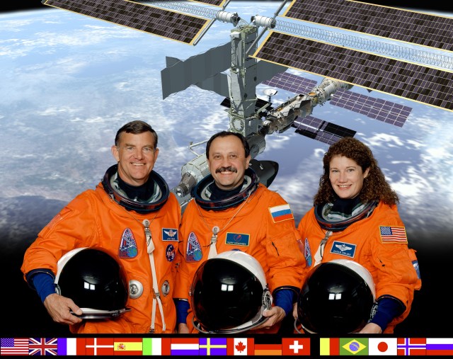 Cosmonaut Yury Usachev (center), Expedition Two mission commander, is flanked by NASA -astronauts James Voss and Susan Helms--who will join him for an extended stay aboard the International Space Station (ISS), beginning in March of this year. Usachev represents the Russian Aviation and Space Agency. The flags representing all the international partners are arrayed at bottom.