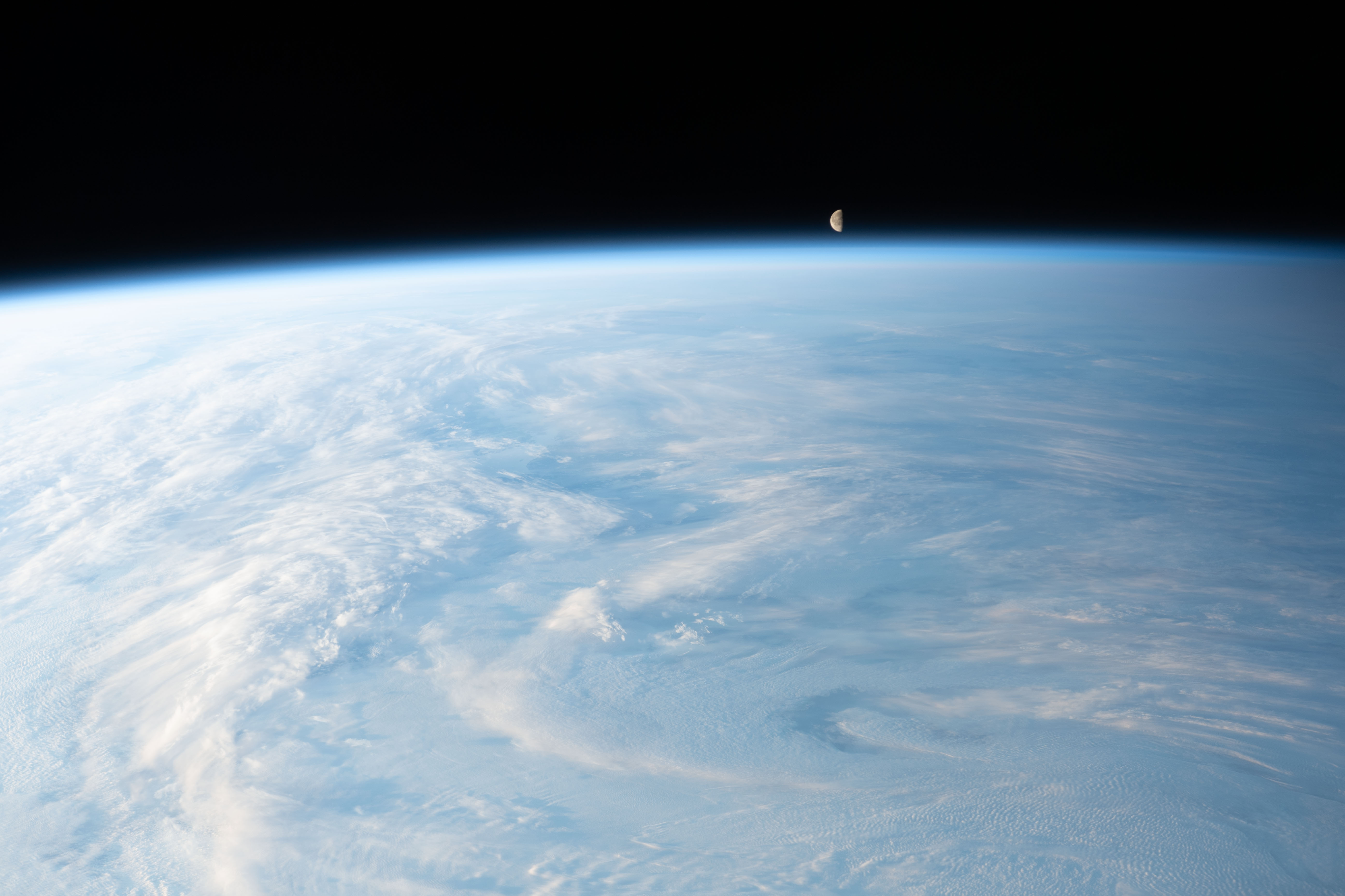 The waning gibbous Moon is pictured just above Earth's horizon in this photograph from the International Space Station as it orbited 262 miles above a cloudy central Asia.
