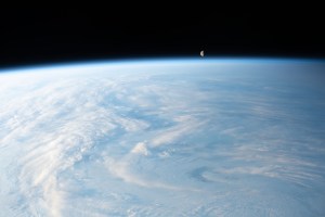 The waning gibbous Moon is pictured just above Earth's horizon in this photograph from the International Space Station as it orbited 262 miles above a cloudy central Asia.