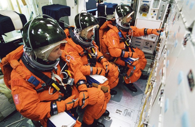 Cosmonauts Vladimir N. Dezhurov (left) and Mikhail Tyurin, both Expedition Three flight engineers; and astronaut Frank L. Culbertson, Jr., Expedition Three commander, participate in mission training in one of the high fidelity trainers/mockups in the Systems Integration Facility at Johnson Space Center (JSC). The three are seated on the mid deck for an emergency egress training session. Dezhurov and Tyurin are affiliated with Rosaviakosmos. The Expedition Three crew is scheduled to launch aboard the Space Shuttle Discovery this summer to begin a lengthy stay onboard the International Space Station (ISS).