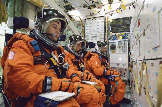 Cosmonauts Vladimir N. Dezhurov (left) and Mikhail Tyurin, both Expedition Three flight engineers; and astronaut Frank L. Culbertson, Jr., Expedition Three commander, participate in mission training in one of the high fidelity trainers/mockups in the Systems Integration Facility at Johnson Space Center (JSC). The three are seated on the mid deck for an emergency egress training session. Dezhurov and Tyurin are affiliated with Rosaviakosmos. The Expedition Three crew is scheduled to launch aboard the Space Shuttle Discovery this summer to begin a lengthy stay onboard the International Space Station (ISS).