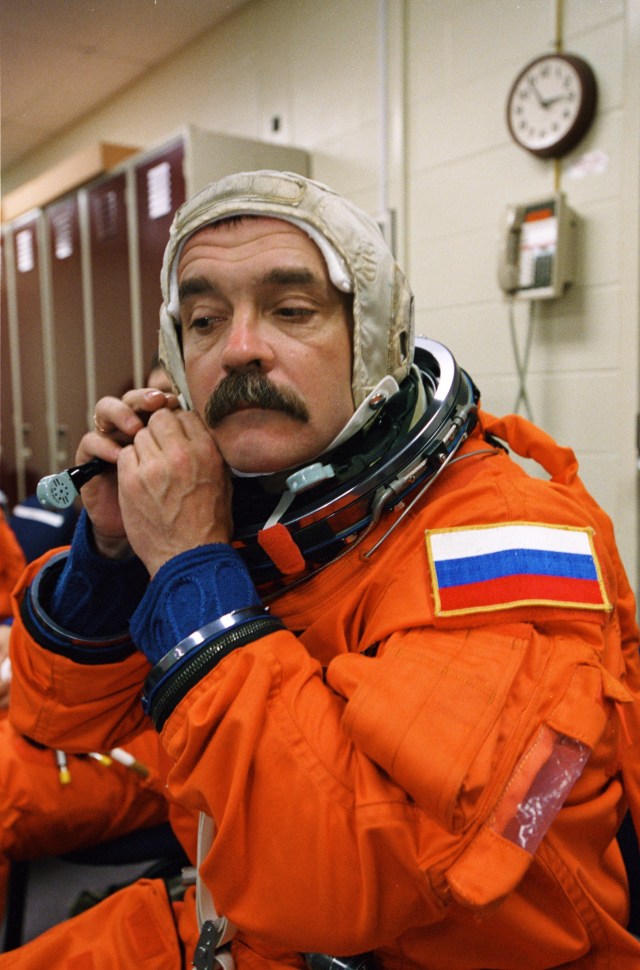 Cosmonaut Mikhail Tyurin, Expedition Three flight engineer representing Rosaviakosmos, dons a training version of the full-pressure launch and entry suit prior to a training session in one of the trainer/mockups (out of frame) in the Johnson Space Center’s Systems Integration Facility.