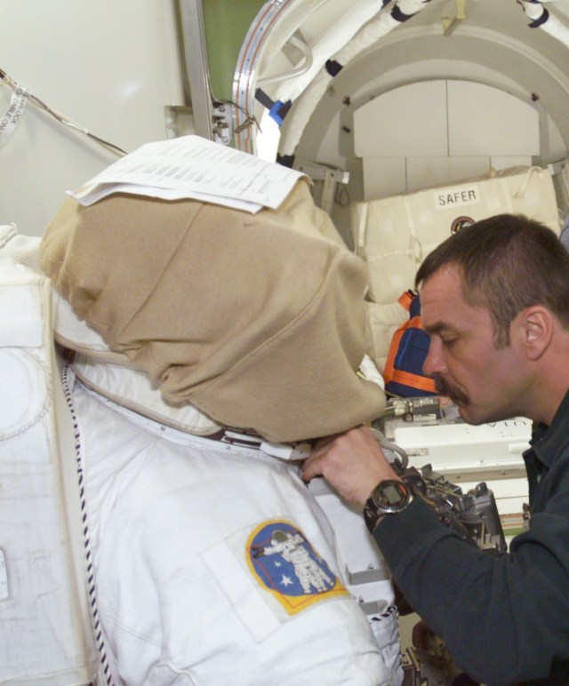 Cosmonaut Mikhail Tyurin, Expedition Three flight engineer, works with a training version of the Extravehicular Mobility Unit (EMU) in the International Space Station (ISS) Airlock trainer/mockup in the Systems Integration Facility at Johnson Space Center (JSC). Tyurin is affiliated with Rosaviakosmos.
