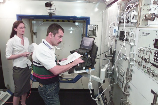 Cosmonaut Mikhail Tyurin, Expedition Three flight engineer representing Rosaviakosmos, assisted by trainer Dea Taylor, is photographed during Human Research Facility (HRF) Rack training in the International Space Station (ISS) Destiny laboratory mockup/trainer at the Johnson Space Center’s Systems Integration Facility.