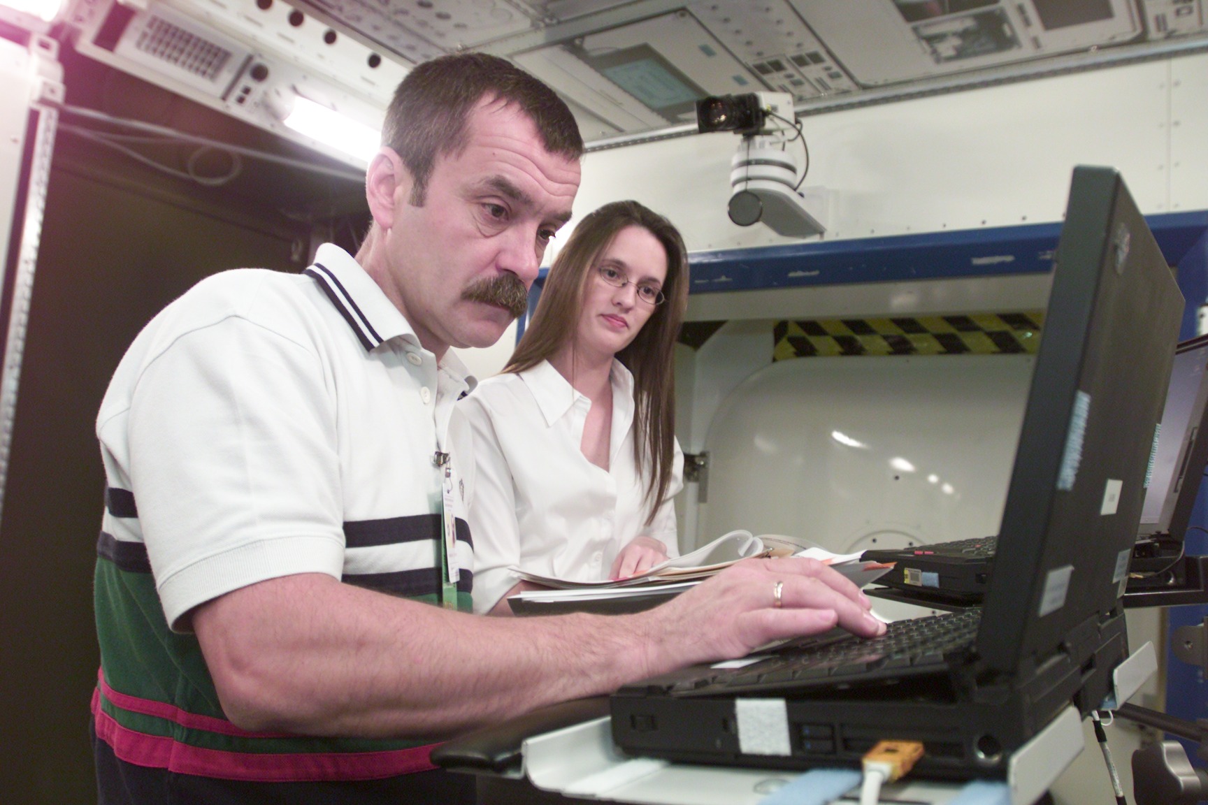 Cosmonaut Mikhail Tyurin, Expedition Three flight engineer representing Rosaviakosmos, assisted by trainer Dea Taylor, is photographed during Human Research Facility (HRF) Rack training in the International Space Station (ISS) Destiny laboratory mockup/trainer at the Johnson Space Center’s Systems Integration Facility.