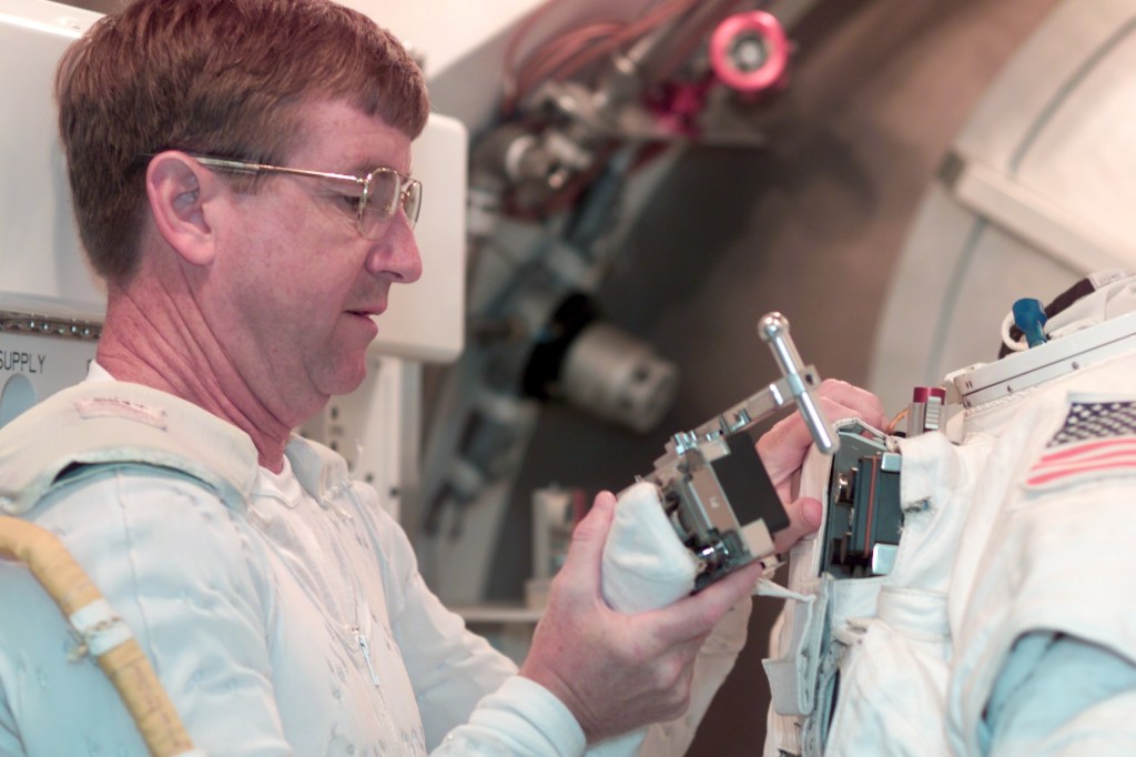 Astronaut Frank L. Culbertson, Jr., Expedition Three commander, participates in an Extravehicular Mobility Unit (EMU) fit check in one of the Space Station Airlock Test Article (SSATA) in the Crew Systems Laboratory at the Johnson Space Center (JSC). Culbertson is wearing the thermal undergarment that complements the EMU.