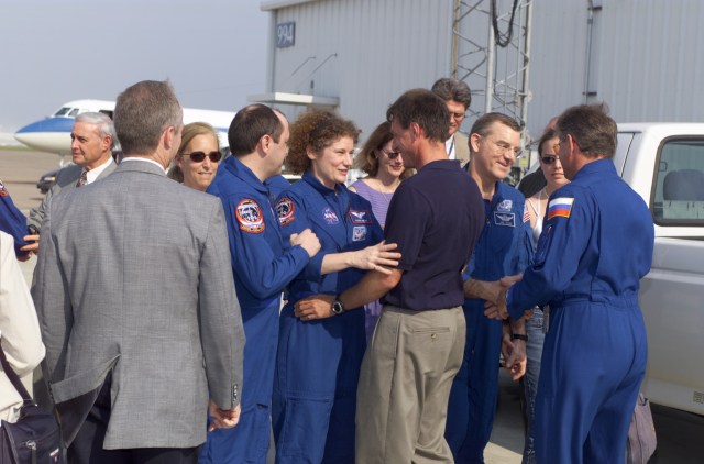 The STS-105 and Expedition Two crews meet their families and friends during the crew return ceremonies at Ellington Field. Among the crowd are Johnson Space Center's (JSC) Acting Director Roy Estess (back left), astronaut Marsha S. Ivins (third from the left), cosmonaut Yury V. Usachev (fourth from the left), Expedition Two mission commander, Susan J. Helms (fifth from the left), Expedition Two flight engineer, James S. Voss (third from the right), Expedition Two flight engineer, and cosmonaut Vasili V. Tsibliyev. The STS-105 crew delivered the Expedition Three crew and supplies to the International Space Station (ISS) and brought the Expedition Two crew back to Earth.