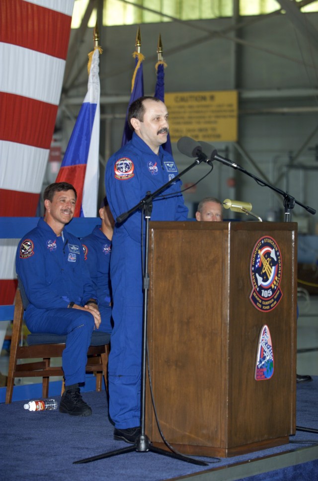 Yury V. Usachev of Rosaviakosmos, Expedition Two mission commander, speaks from the podium in Hangar 990 at Ellington Field during the STS-105 and Expedition Two crew return ceremonies. The STS-105 crew listens in the background. Usachev and fellow Expedition Two crewmembers Susan J. Helms and James S. Voss spent five months aboard the International Space Station (ISS).