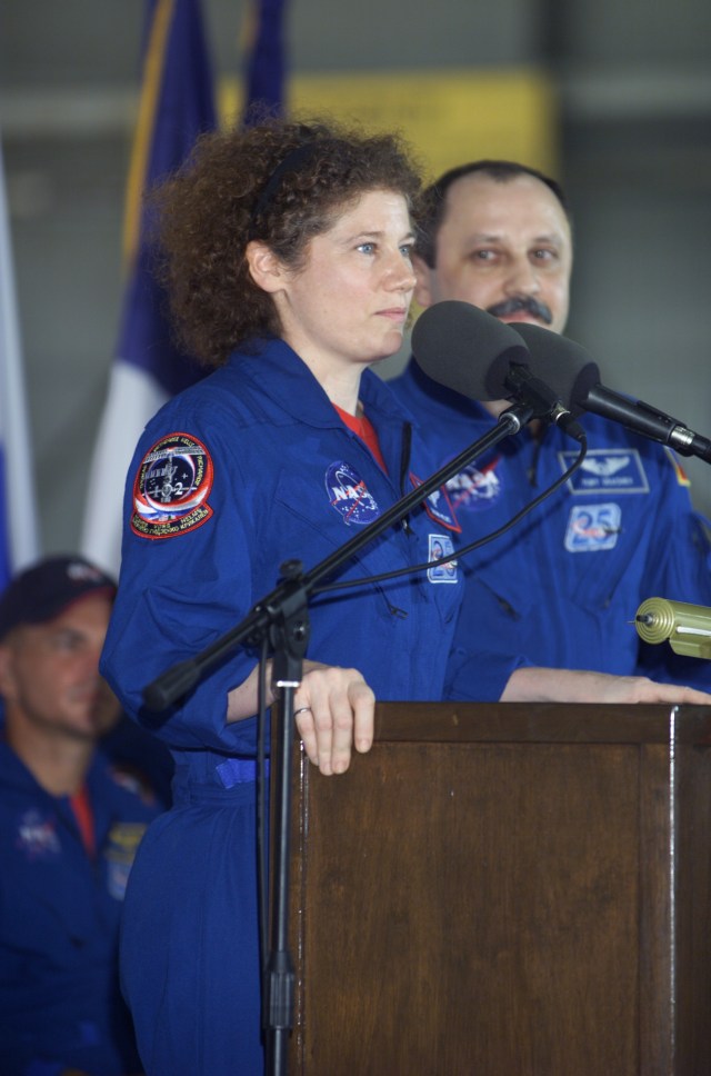 Susan J. Helms, Expedition Two flight engineer, speaks from the podium in Hangar 990 at Ellington Field during the STS-105 and Expedition Two crew return ceremonies. Yury V. Usachev of Rosaviakosmos, Expedition Two mission commander, stands to Helms' left. Helms, Usachev and fellow Expedition Two crewmember James S. Voss spent five months aboard the International Space Station (ISS).