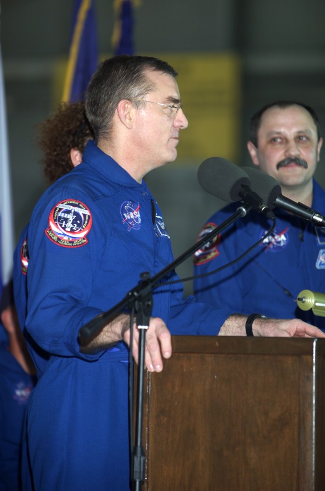 James S. Voss, Expedition Two flight engineer, speaks from the podium in Hangar 990 at Ellington Field during the STS-105 and Expedition Two crew return ceremonies. Yury V. Usachev of Rosaviakosmos, Expedition Two mission commander, stands to Voss' left. Voss, Usachev and fellow Expedition Two crewmember Susan J. Helms spent five months aboard the International Space Station (ISS).