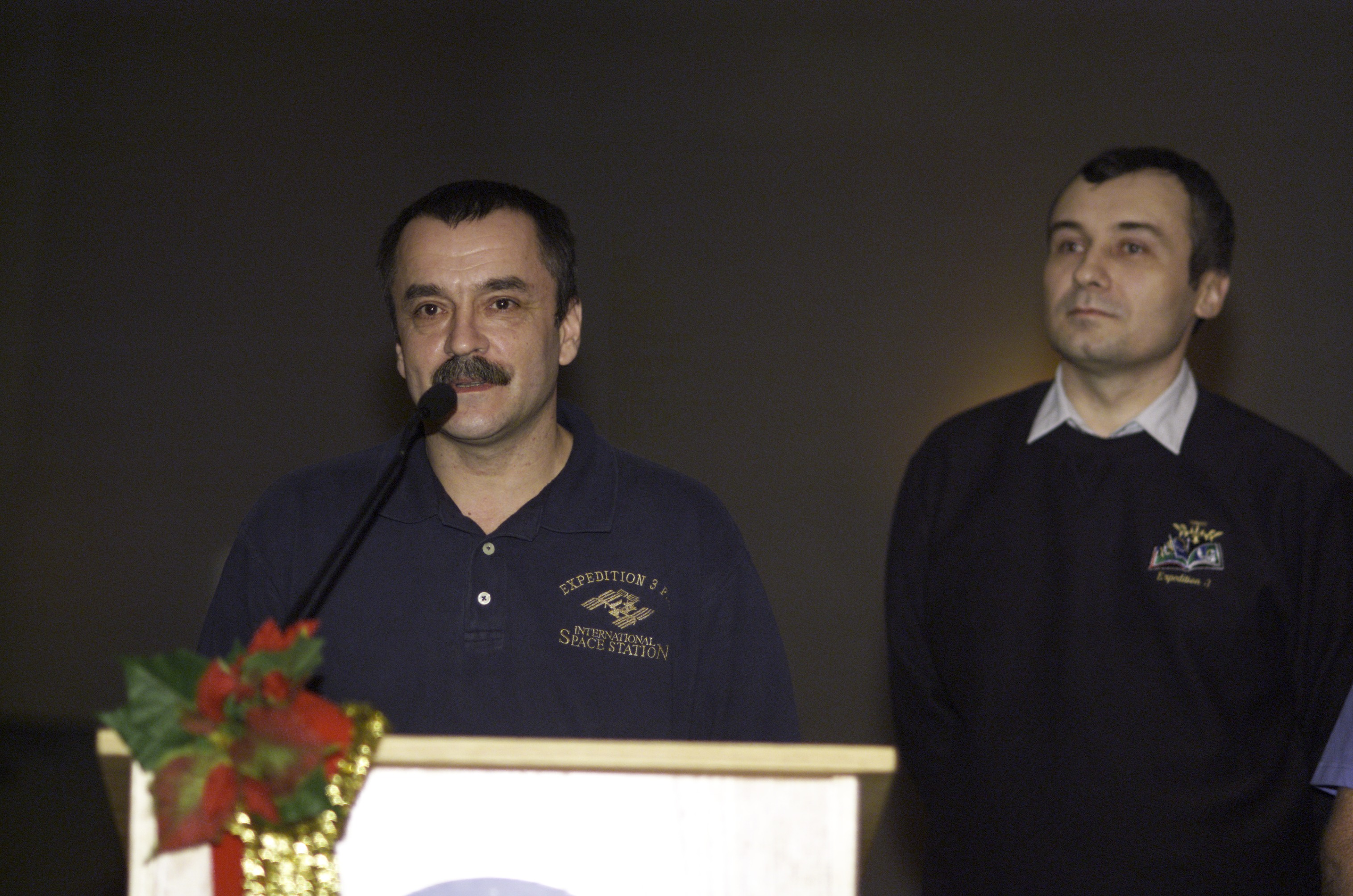 Cosmonaut Mikhail Tyurin, joined by cosmonaut Vladimir N. Dezhurov, both Expedition Three flight engineers representing Rosaviakosmos, speaks from the lectern in the ballroom of the Gilruth Center at Johnson Space Center (JSC) during the Expedition Three Welcome Home ceremony.
