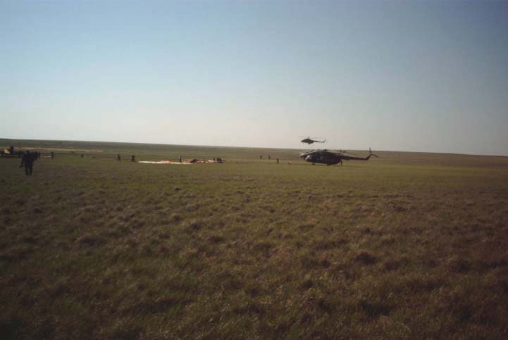 This wide shot reveals the post-landing scene of the Soyuz TM-33 spacecraft not far from the town of Arkalyk, Kazakhstan, soon after the Soyuz 4 ISS Taxi mission ended successfully there. The spacecraft is out of frame but its landing parachute can be seen near center frame. Also pictured are two of the several helicopters that delivered aid and rescue teams to the site soon after landing, which occurred at 7:52 a.m. Moscow time. Onboard were Yuri Gidzenko, commander; Roberto Vittori, flight engineer; and space flight participant Mark Shuttleworth of South Africa. Gidzenko is with Rosaviakosmos and Vittori represents the European Space Agency (ESA). Photo Credit: NASA/Marty Linde