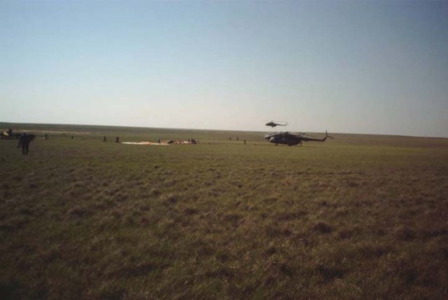This wide shot reveals the post-landing scene of the Soyuz TM-33 spacecraft not far from the town of Arkalyk, Kazakhstan, soon after the Soyuz 4 ISS Taxi mission ended successfully there. The spacecraft is out of frame but its landing parachute can be seen near center frame. Also pictured are two of the several helicopters that delivered aid and rescue teams to the site soon after landing, which occurred at 7:52 a.m. Moscow time. Onboard were Yuri Gidzenko, commander; Roberto Vittori, flight engineer; and space flight participant Mark Shuttleworth of South Africa. Gidzenko is with Rosaviakosmos and Vittori represents the European Space Agency (ESA). Photo Credit: NASA/Marty Linde