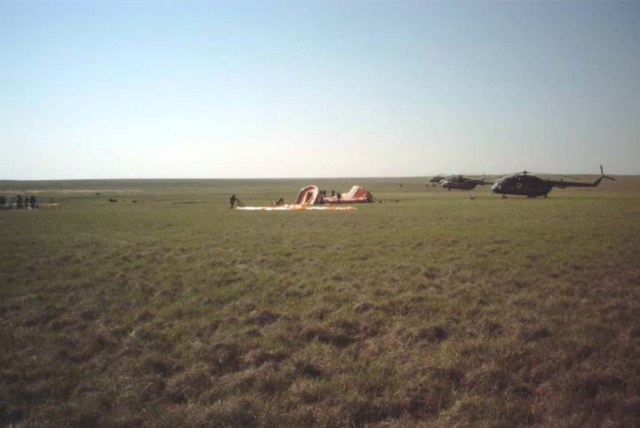 This wide shot was taken near the landing site of the Soyuz TM-33 spacecraft not far from the town of Arkalyk, Kazakhstan, soon after the Soyuz 4 ISS Taxi mission ended there. The spacecraft's landing parachute can be seen lying on the ground, near the early stages of a medical tent, which required about two minutes to deploy. Helicopters with aid and rescue team members approached the site soon after landing at 7:52 a.m. Moscow time. Onboard were Yuri Gidzenko, commander; Roberto Vittori, flight engineer; and space flight participant Mark Shuttleworth of South Africa. Gidzenko is with Rosaviakosmos and Vittori represents the European Space Agency (ESA). Photo Credit: NASA/Marty Linde