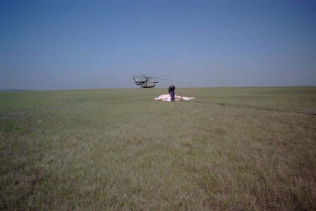 This wide shot reveals the post-landing scene of the Soyuz TM-33 spacecraft not far from the town of Arkalyk, Kazakhstan, soon after the Soyuz 4 ISS Taxi mission ended successfully there. The Soyuz is out of frame in this scene, which shows a rescue team member gathering the spacecraft's landing parachute and a MI-6 helicopter on the ground in the background. Landing occurred around 7:52 a.m. Moscow time. Onboard were Yuri Gidzenko, commander; Roberto Vittori, flight engineer; and space flight participant Mark Shuttleworth of South Africa. Gidzenko is with Rosaviakosmos and Vittori represents the European Space Agency (ESA). Photo Credit: NASA/Marty Linde