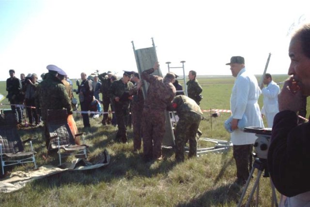 Rescue team members assemble an extraction stand to assist the ISS Soyuz 4 taxi crew members to egress from their Soyuz TM-33 spacecraft at the landing site near Arkalyk, Kazakhstan. The spacecraft, with its crew of three still inside, is out of frame here in this scene taken minutes after the landing, which occurred around 7:52 a.m. Moscow time on May 5, 2002. The crew members were Yuri Gidzenko, commander; Roberto Vittori, flight engineer; and space flight participant Mark Shuttleworth of South Africa. Gidzenko is with Rosaviakosmos and Vittori represents the European Space Agency (ESA). Photo Credit: NASA/Marty Linde