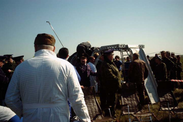 Aid and rescue team members prepare to equip the Soyuz TM-33 spacecraft with a special device called the crew extraction stand. The stand, which has both a ladder and a slide, makes it possible for the crewmembers to egress the spacecraft without their feet touching the ground. Three chairs await the crewmembers in the foreground. Having spent 10 days in space, the majority of that time onboard the International Space Station (ISS), still inside the spacecraft are Yuri Gidzenko, commander; Roberto Vittori, flight engineer; and space flight participant Mark Shuttleworth of South Africa. Gidzenko is with Rosaviakosmos and Vittori represents the European Space Agency (ESA). Photo Credit: NASA/Marty Linde Photo Credit: NASA/Marty Linde