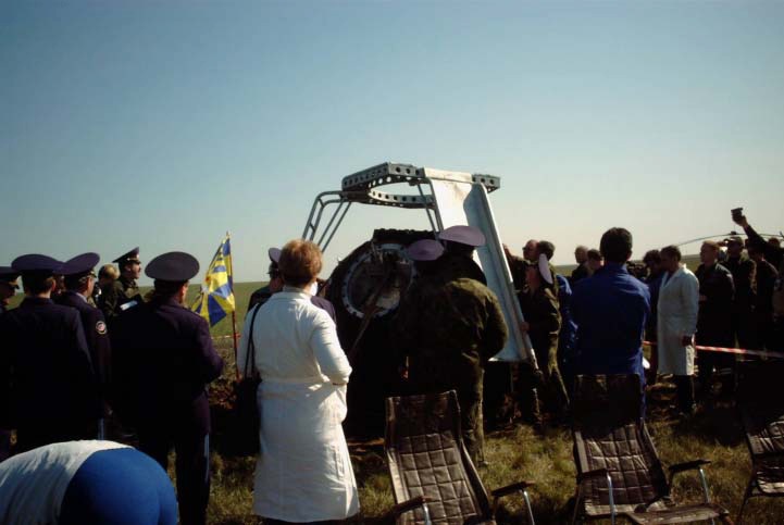 Aid and rescue team members prepare to equip the Soyuz TM-33 spacecraft with a special device called the crew extraction stand soon after the spacecraft soft-landed to complete the successful Soyuz 4 taxi mission. The device has both a ladder and a slide, which make it possible for the crewmembers to egress the spacecraft without their feet touching the ground. Three chairs await the crewmembers in the foreground. Having spent 10 days in space, the majority of that time onboard the International Space Station (ISS), and still inside the spacecraft are Yuri Gidzenko, commander; Roberto Vittori, flight engineer; and space flight participant Mark Shuttleworth of South Africa. Gidzenko is with Rosaviakosmos and Vittori represents the European Space Agency (ESA). Photo Credit: NASA/Marty Linde