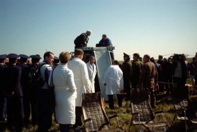 Wearing white lab coats, a medical team waits for the ISS Soyuz 4 taxi crew members to egress from their Soyuz TM-33 spacecraft at the landing site near Arkalyk, Kazakhstan. The Crew Surgeon is in the blue flight suit with the medical packpack. Three chairs (foreground) await the three, who have been in space for approximately 10 days. The spacecraft landed around 7:52 a.m. Moscow time on May 5, 2002. The crew members are Yuri Gidzenko, commander; Roberto Vittori, flight engineer; and space flight participant Mark Shuttleworth of South Africa. Gidzenko is with Rosaviakosmos and Vittori represents the European Space Agency (ESA). Photo Credit: NASA/Marty Linde