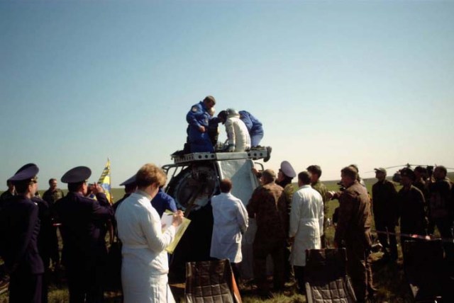 This medium shot reveals the post-landing scene of the Soyuz TM-33 spacecraft not far from the town of Arkalyk, Kazakhstan, soon after the Soyuz 4 ISS Taxi mission ended successfully there. The hatch is now open and rescue personnel assist Yuri Gidzenko, commander, who was the first cosmonaut to egress. Landing occurred at 7:52 a.m. Moscow time. Onboard with Gidzenko were Roberto Vittori, flight engineer; and space flight participant Mark Shuttleworth of South Africa. Gidzenko is with Rosaviakosmos and Vittori represents the European Space Agency (ESA). Photo Credit: NASA/Marty Linde