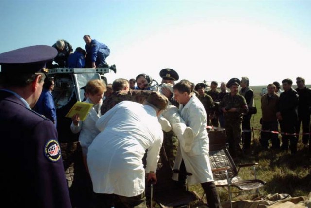 Aid and rescue team members ease Yuri Gidzenko, Soyuz 4 commander, into a chair following his egress from the Soyuz TM-33 spacecraft in the background. The Soyuz touched down at 7:52 a.m. (Moscow time) in a field near Arkalyk, Kazakhstan. Photo Credit: NASA/Marty Linde