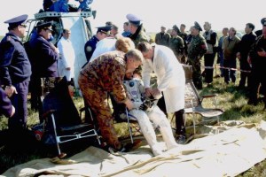 Aid and rescue team members ease Yuri Gidzenko, Soyuz 4 commander, into a chair following his egress from the Soyuz TM-33 spacecraft in the background. Ground crewmembers begin to assist the egress of Roberto Vittori (not visible), flight engineer. The Soyuz touched down at 7:52 a.m. (Moscow time) in a field near Arkalyk, Kazakhstan. Photo Credit: NASA/Marty Linde