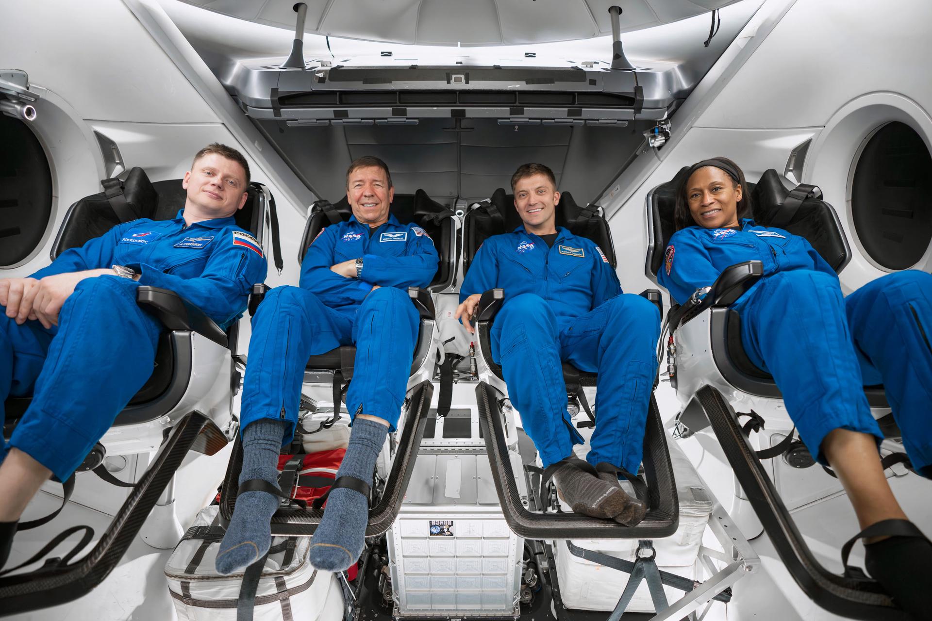 Four astronauts sit inside a SpaceX Dragon crew capsule.