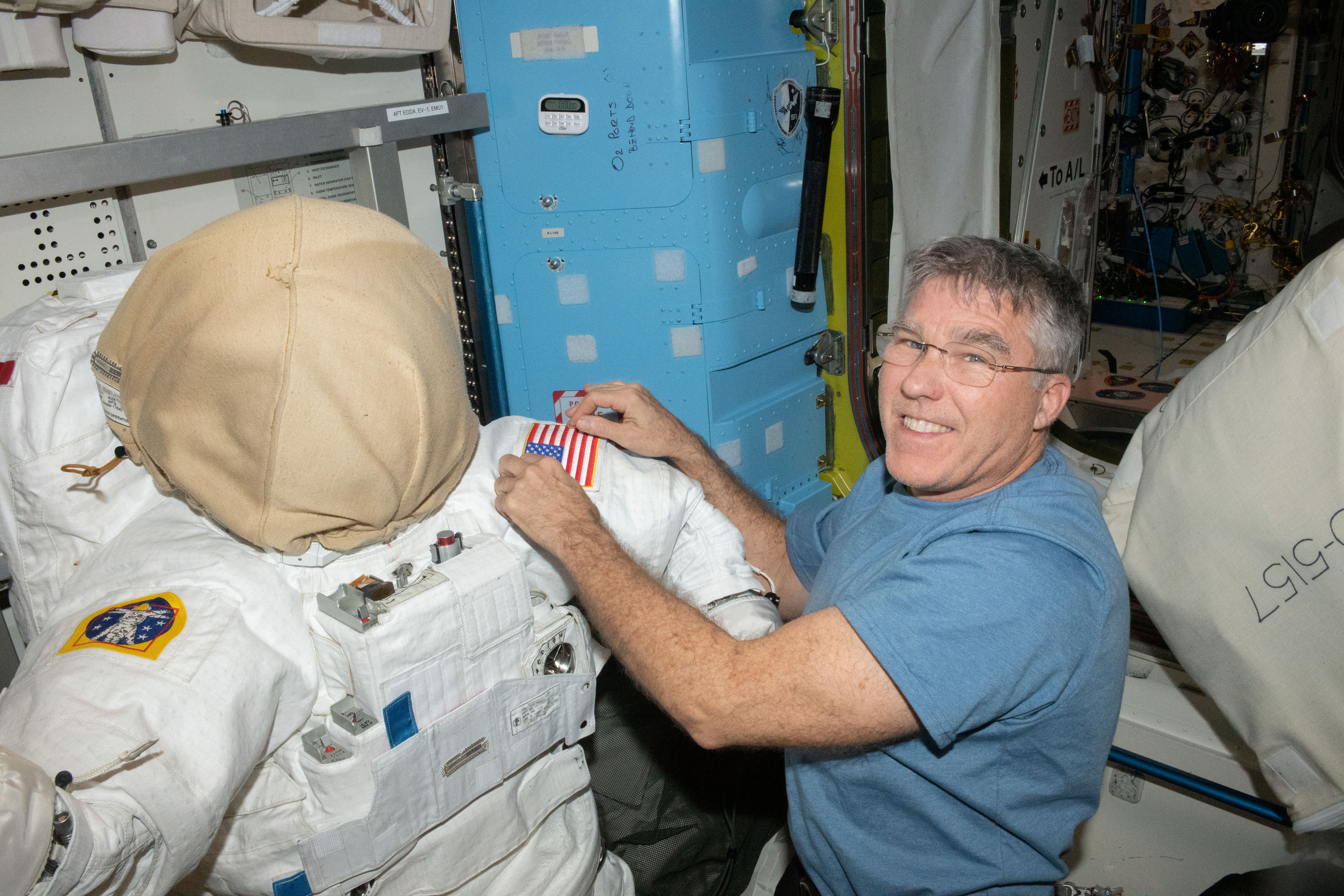 NASA astronaut and Expedition 69 Flight Engineer Stephen Bowen prepares an Extravehicular Mobility Unit, or spacesuit, inside the International Space Station's Quest airlock for an upcoming spacewalk.