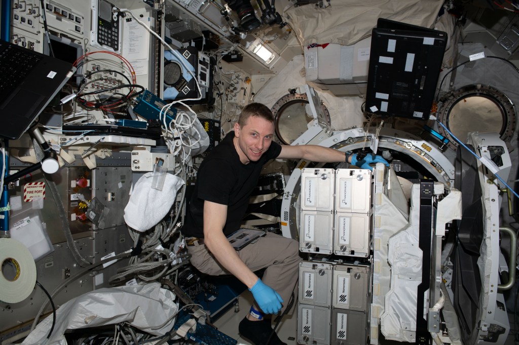NASA astronaut and Expedition 69 Flight Engineer Woody Hoburg removes the NanoRacks CubeSat Deployer from the Kibo laboratory module's airlock.