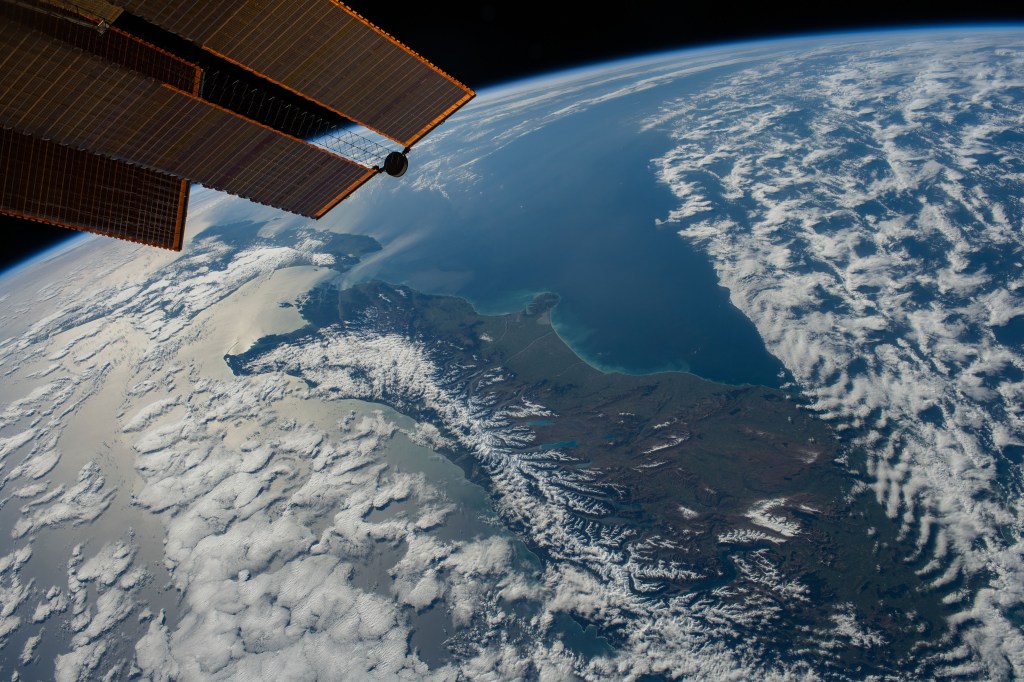 New Zealand, with its snow-capped Southern Alps mountain range, is pictured between two partly cloudy bodies of water, the Tasman Sea and the Pacific Ocean, as the International Space Station orbited 271 miles above.
