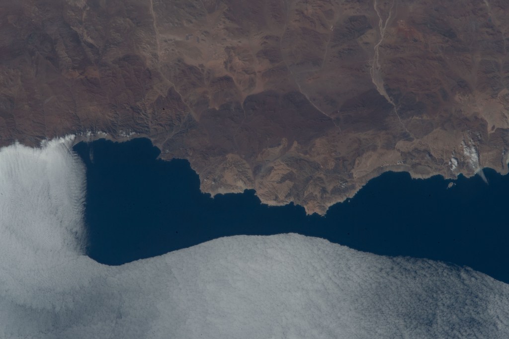 The mountainous coast of Pan de Azucar, a National Park in Chile, is met by a sheet of clouds moving in from the Pacific Ocean as the International Space Station soared 263 miles above.