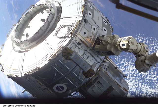 The newly-installed Canadarm2, Space Station Remote Manipulator System (SSRMS), controlled by Susan J. Helms, Expedition Two flight engineer, maneuvers the Quest Airlock in the proper position to be mated onto the starboard side of Unity Node 1 during the first extravehicular activity (EVA) of the STS-104 mission. The Earth backdrops this image, exposed with a digital still camera.